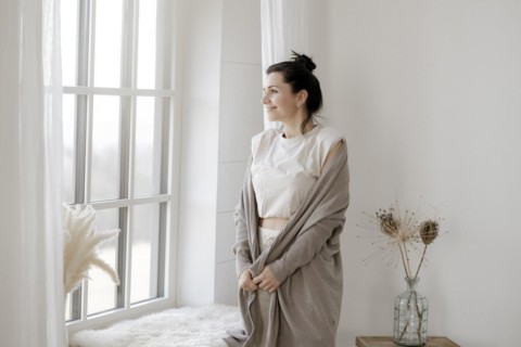 Dark-haired woman stands relaxed at the window
