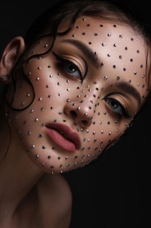 Beautiful woman with creative hairstyle and makeup with rhinestones. Beauty face. Photo taken in the studio
