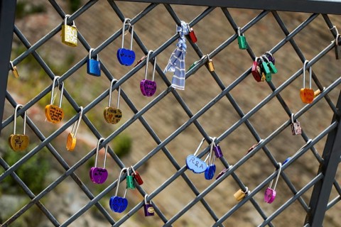 Many colorful metal love padlocks on fence