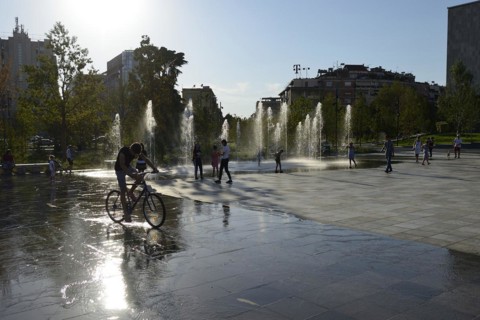 Fountain and cyclists in the backlight