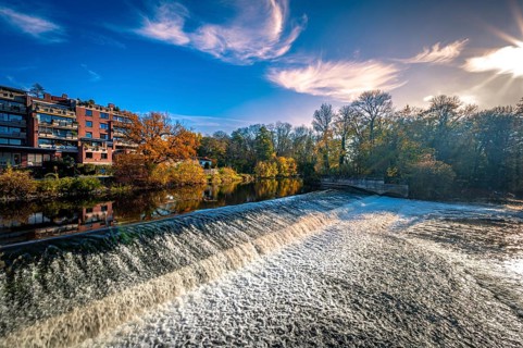 The Leineinsel waterfall next to the Leineinsel residential area in the district of Doehren in autumn with veil clouds