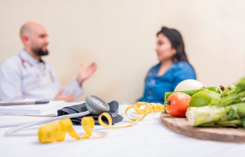 Nutritionist man with woman patient in office. Nutritionist talking to female patient with focus on the fruits in the foreground. Concept of nutritionist advising female client