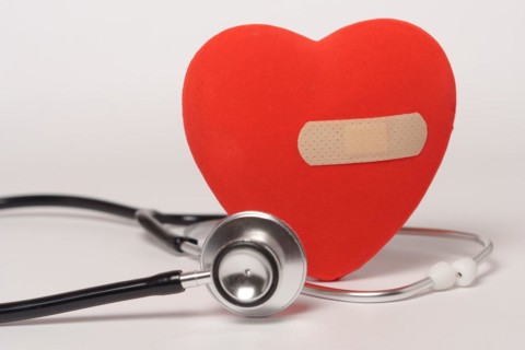 Red heart with band-aid and stethoscope isolated on white background