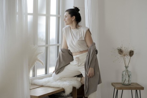 Dark-haired woman sits relaxed at the window