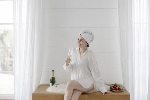 Portrait of an attractive woman with a towel on her head drinking champagne