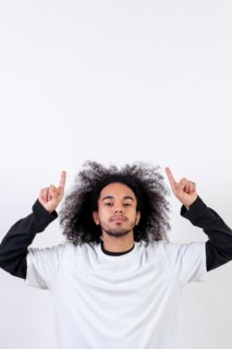 Pointing above a copy paste space. Young man with afro hair on white background