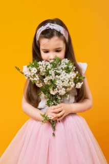Cute little child sniffing the bouquet of spring flowers