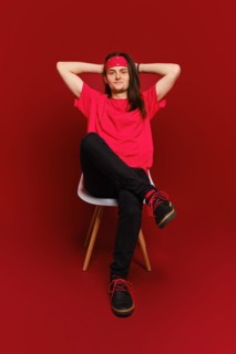 Man threw his hands behind his head and sits relaxed on chair in red studio