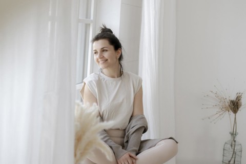Dark-haired woman sits relaxed at the window