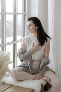 Satisfied woman sits gratefully by the window