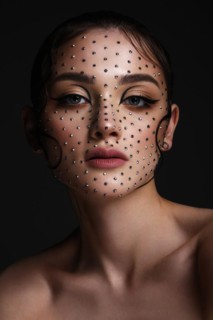 Beautiful woman with creative hairstyle and makeup with rhinestones. Beauty face. Photo taken in the studio