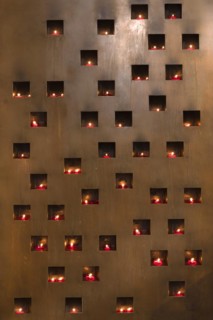 Burning sacrificial candles in a metal wall