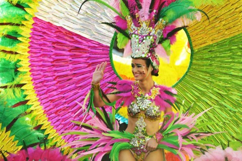 Multicoloured people of all ages praise the parade in Carnival