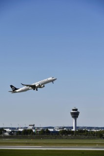Taking off Star Alliance AIR DOLOMITI EMBRAER ERJ-195 on runway south with tower