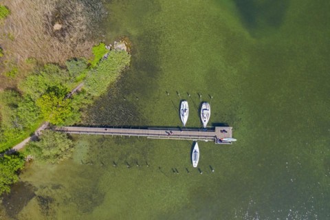 Aerial view over sailing boats moored at wooden jetty in lake Ratzeburger