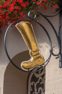 Gold-coloured boot as nose sign of a shoe shop