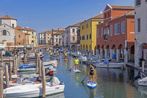 Tourists standup paddleboarding on canal Vena at Chioggia
