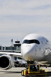 Lufthansa Airbus A350-900 towing with push-back truck in front of Terminal 2 with tower