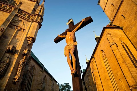 Jesus Christ on the cross between Erfurt Cathedral and Severi Church in early morning light