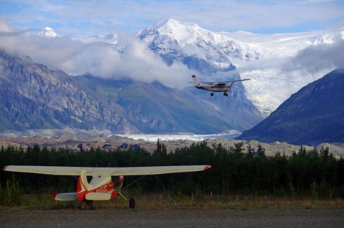 Two small bush planes in front of huge glaciers