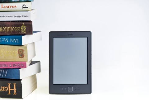 Kindle e reader with a large pile of books