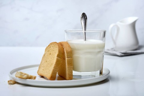 Rusk and glass of milk with spoon