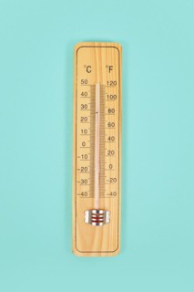 Wooden thermometer on green background