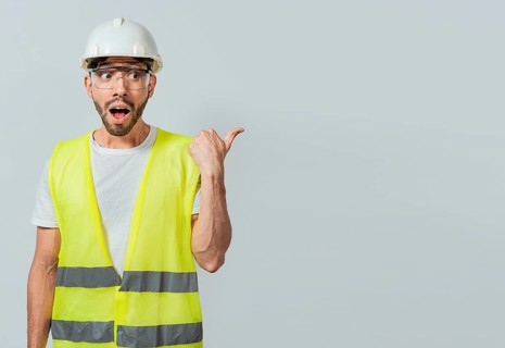Surprised engineer pointing to the side. Surprised face construction worker pointing at an advertisement. Engineer man pointing to side. Surprised face engineer pointing finger to the right