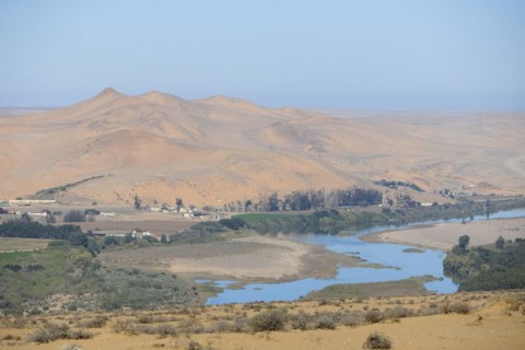 Orange River, also known as the Orange River, on the border between Namibia and South Africa, sand dunes behind, Oranjemund, Sperrgebiet National Park, also known as Tsau ÇKhaeb National Park, Namibi...