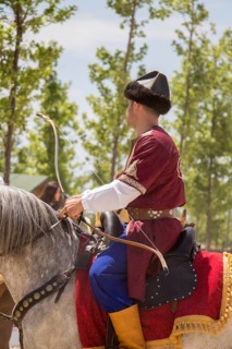 Archer with bow in traditional clothes shooting an arrow