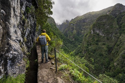 Hikers on a narrow path along a levada, view of forested mountains and gorges, Levada do Caldeirao Verde, Parque Florestal das Queimadas, Madeira, Portugal, Europe