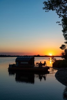 Two men sitting on a houseboat at sunset, house raft, in front of the island Kiehnwerder, Breitlingsee, Brandenburg an der Havel, Havelland, Brandenburg, Germany, Europe