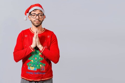 Man with christmas hat with praying hands isolated. Guy with hands together praying in christmas isolated, concept of person with christmas hat praying and making a wish