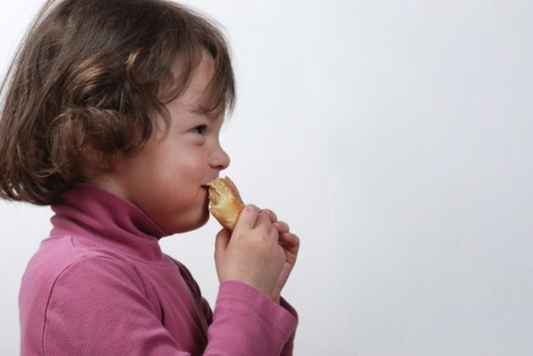 A young girl eating a bun