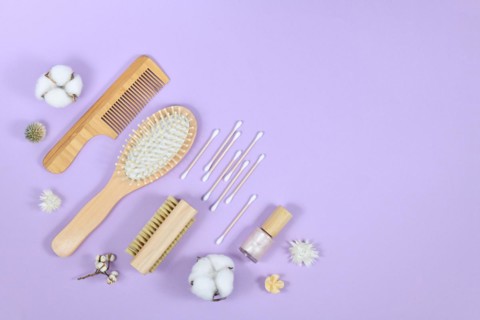 Eco friendly wooden beauty and hygiene products like comb and soap in corner of purple background with copy space