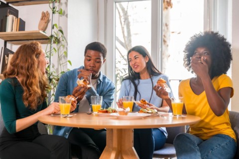 Friends at a breakfast with orange juice and muffins at home, having fun in domestic life