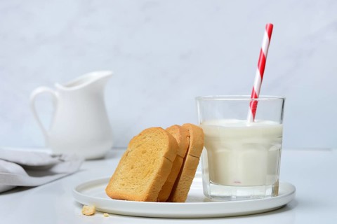 Rusk and glass of milk with drinking straw