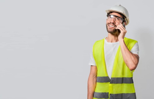 Smiling engineer talking on the phone isolated with copy space. Young builder engineer in vest talking on cell phone isolated. Civil engineer concept talking on cellphone isolated