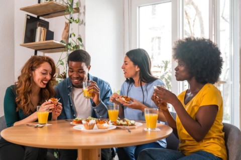 Friends at a breakfast with orange juice and muffins at home, having fun in the morning
