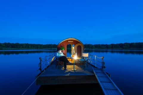 Man sitting in the blue hour on a houseboat, house raft, in front of the island Kiehnwerder, Breitlingsee, Brandenburg an der Havel, Havelland, Brandenburg, Germany, Europe