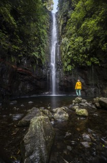 Young woman standing by the river and waterfall Cascata das 25 Fontes, long exposure, Rabacal, Paul da Serra, Madeira, Portugal, Europe