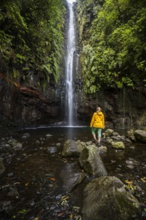Young woman standing by the river and waterfall Cascata das 25 Fontes, long exposure, Rabacal, Paul da Serra, Madeira, Portugal, Europe