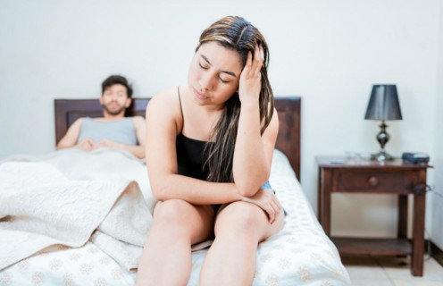 Wife on the edge of the bed arguing with her husband. Upset woman arguing with her husband in bed. Concept of couple problems in bed