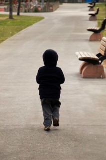 Child walking wooden park bench at a park