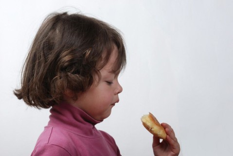 A young girl eating a bun