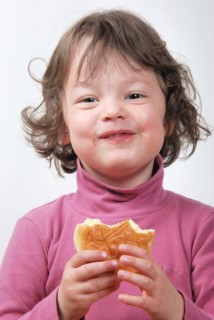 A young girl eating a bun