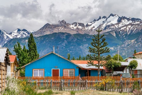Blue wooden house, Cerro Castillo mountain range in the back, Villa Cerro Castillo village, Cerro Castillo National Park, Aysen, Patagonia, Chile, South America