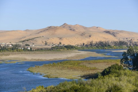 Orange River, also known as the Orange River, on the border between Namibia and South Africa, sand dunes behind, Oranjemund, Sperrgebiet National Park, also known as Tsau ÇKhaeb National Park, Namibi...