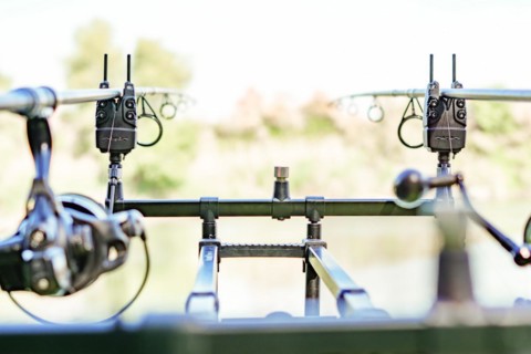 Close-up of a rod holder with alarms and two rods with their reels in fishing action