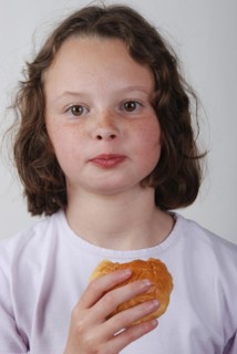 A young girl eating a bun